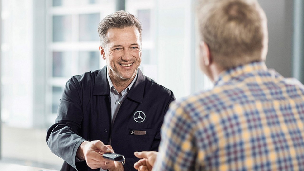 Service-Mitarbeiter übergibt Autoschlüssel an Kunden.