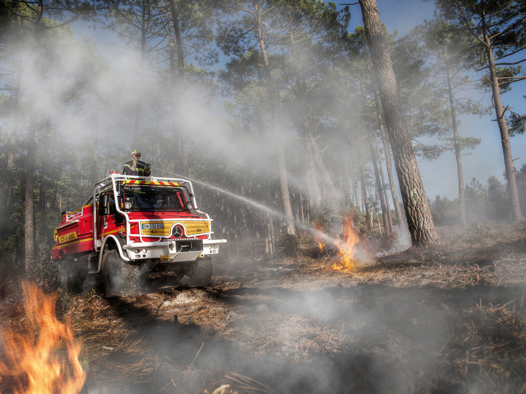 Un Unimog rosso spegne un incendio boschivo.