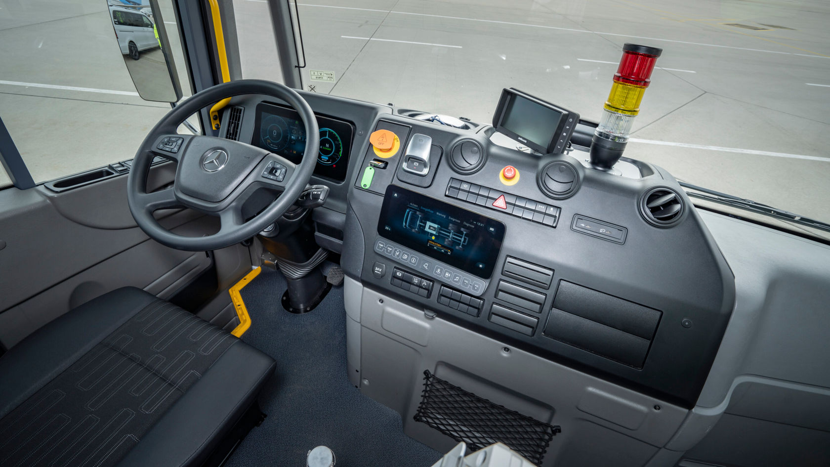 Das Bild zeigt das Cockpit eines eEconic mit Fahrzeuglenkrad, verschiedenen Bedienelementen und einem digitalen Display.