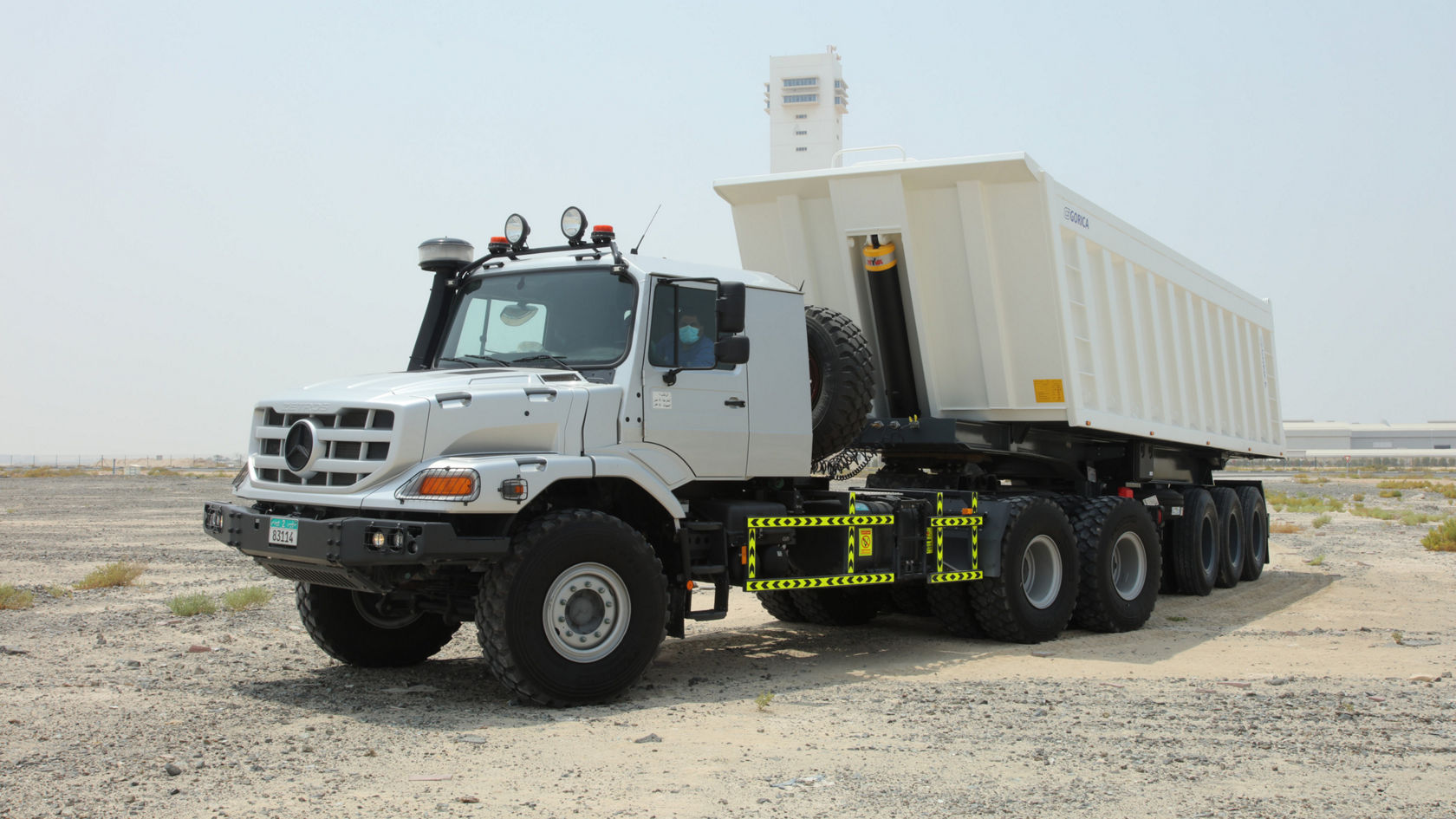 A Mercedes-Benz Zetros truck with a large, open-topped dump body stands on a dry, sandy area, ready for use in difficult terrain.