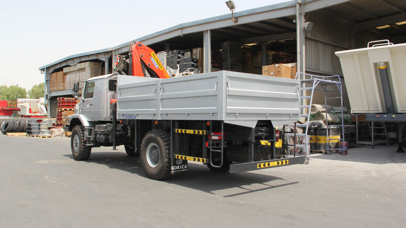 A Mercedes-Benz Zetros with a loading area stands in a storage area. On the loading area is a crane suitable for heavy loads.