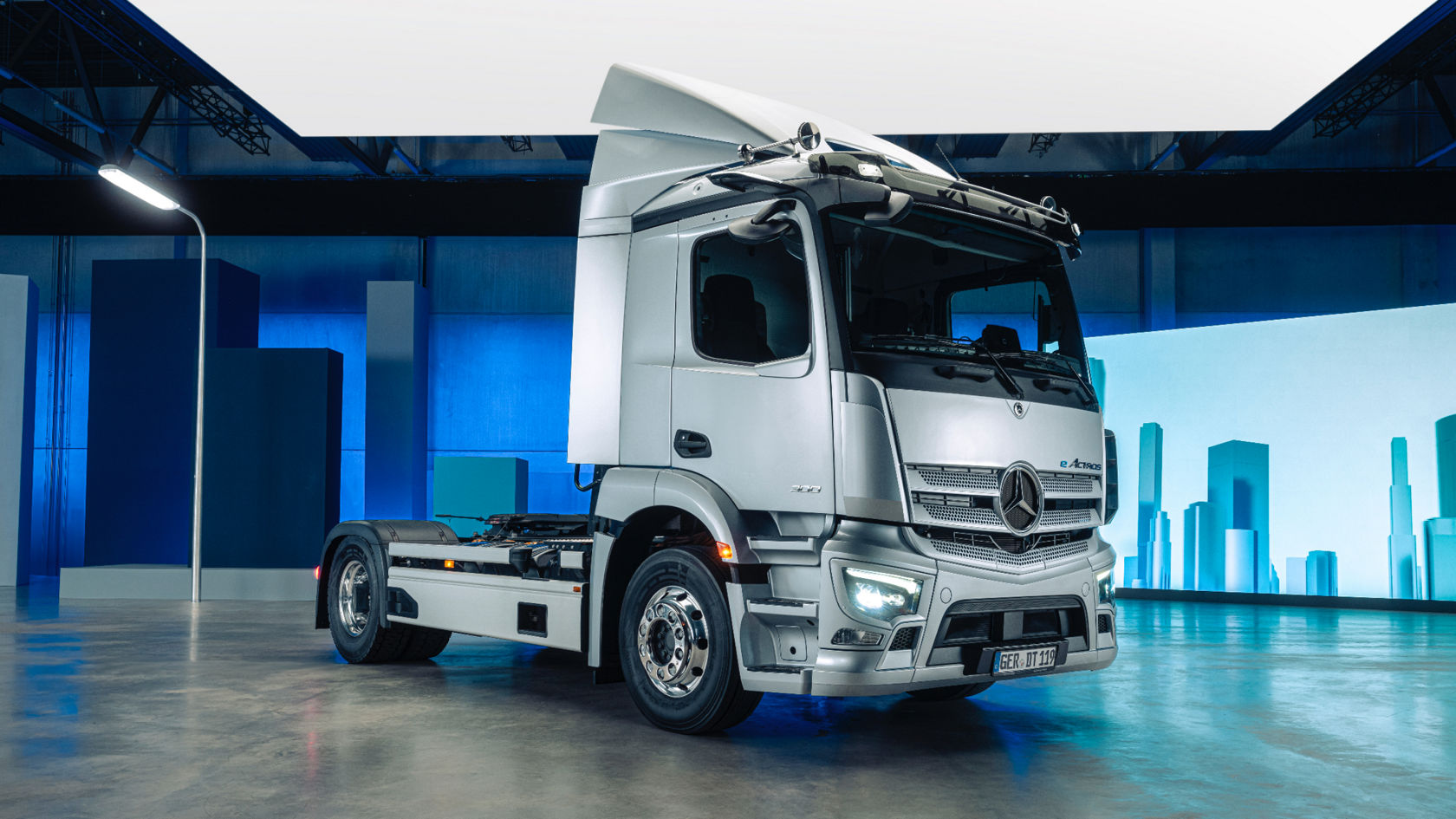银色 eActros 在蓝色背景和风格化建筑元素的现代展览环境中。