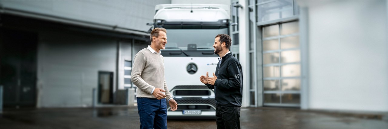 Zwei Männer sprechen vor einem Lkw.