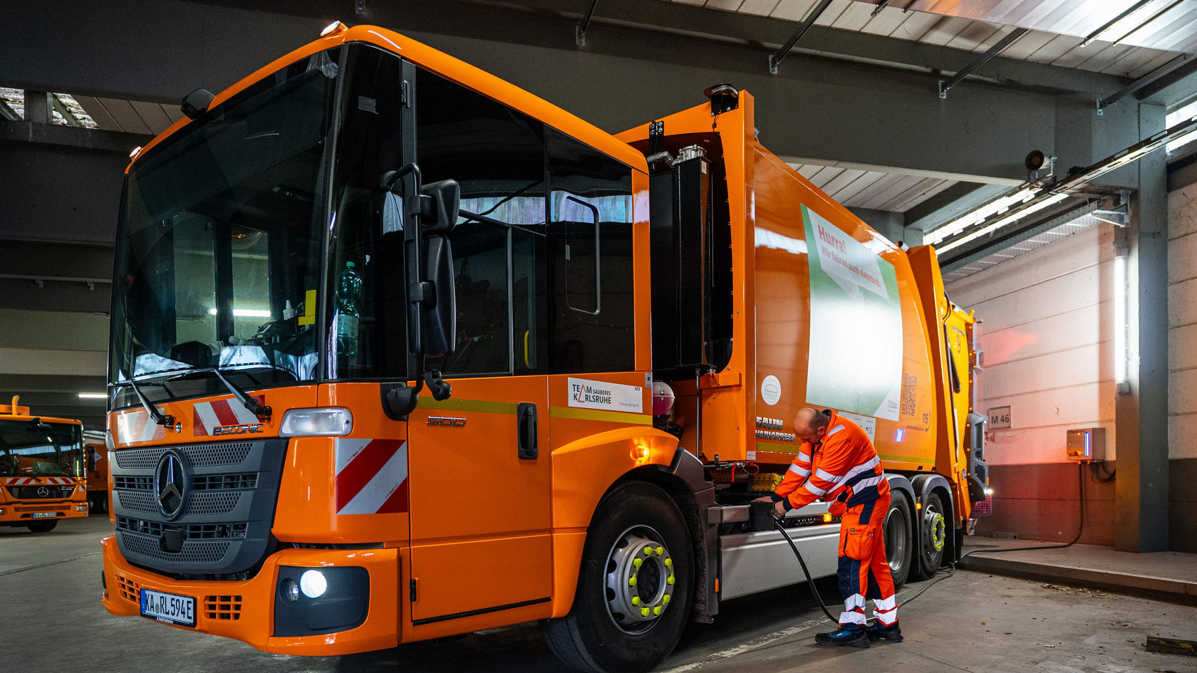 Mitarbeiter steckt im Depot das Ladekabel an den eEconic