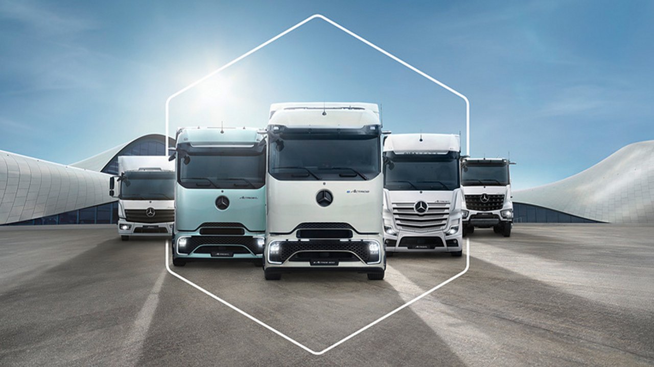 Vier Lkw stehen nebeneinander vor moderner Architektur.