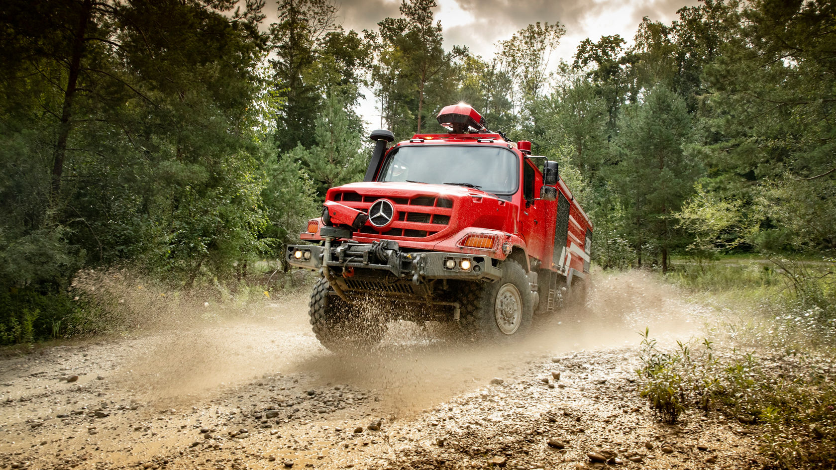 Roter Feuerwehr Zetros fährt durch matschiges Gelände