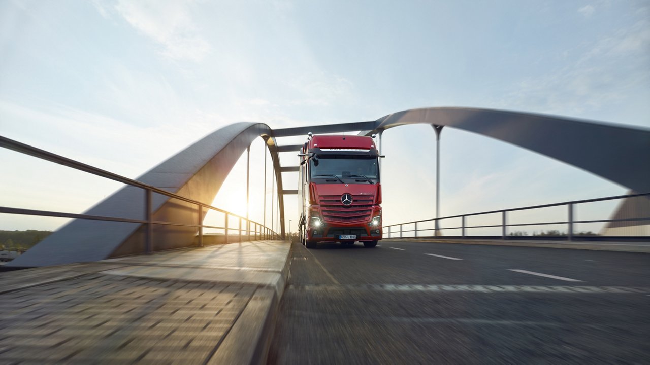 Ein roter Actros L fährt über eine Brücke