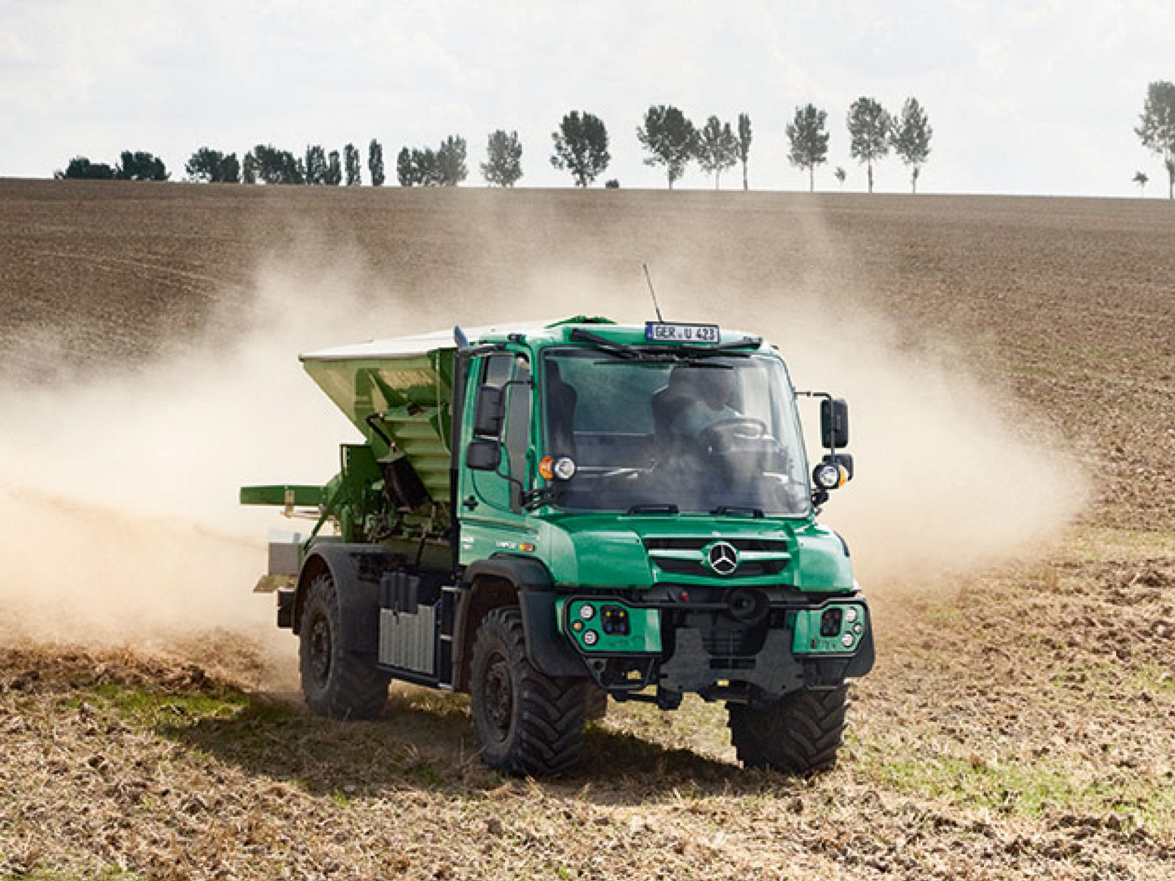 Een groene Unimog werktuigdrager in de landbouw rijdt over een akker.