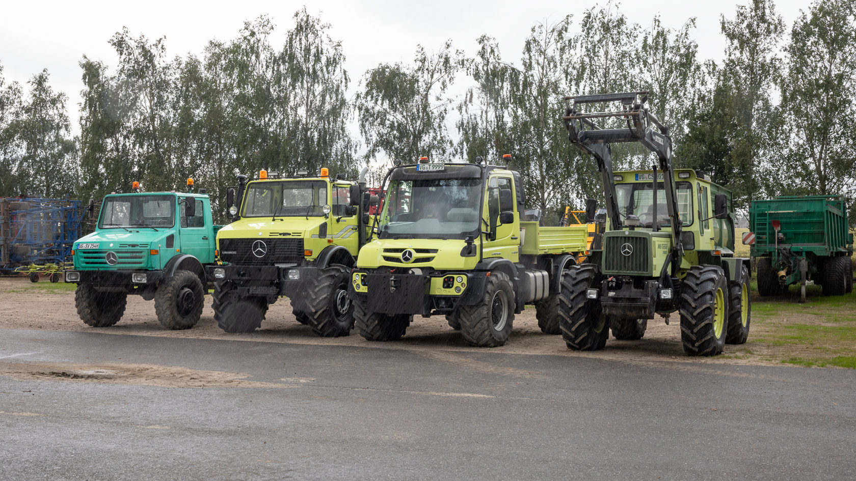 Quatre véhicules Mercedes‑Benz sont côte à côte sur une surface revêtue. Les modèles présentent différentes couleurs et designs, dont le vert et le jaune, et sont destinés à des usages agricoles.